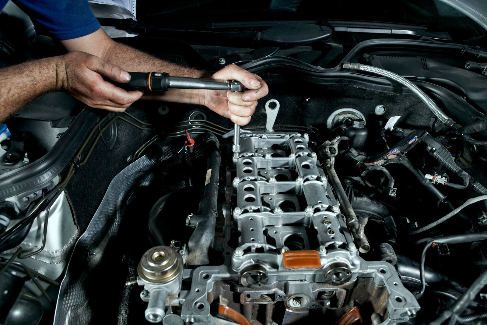 A man is working on a car engine with a wrench.