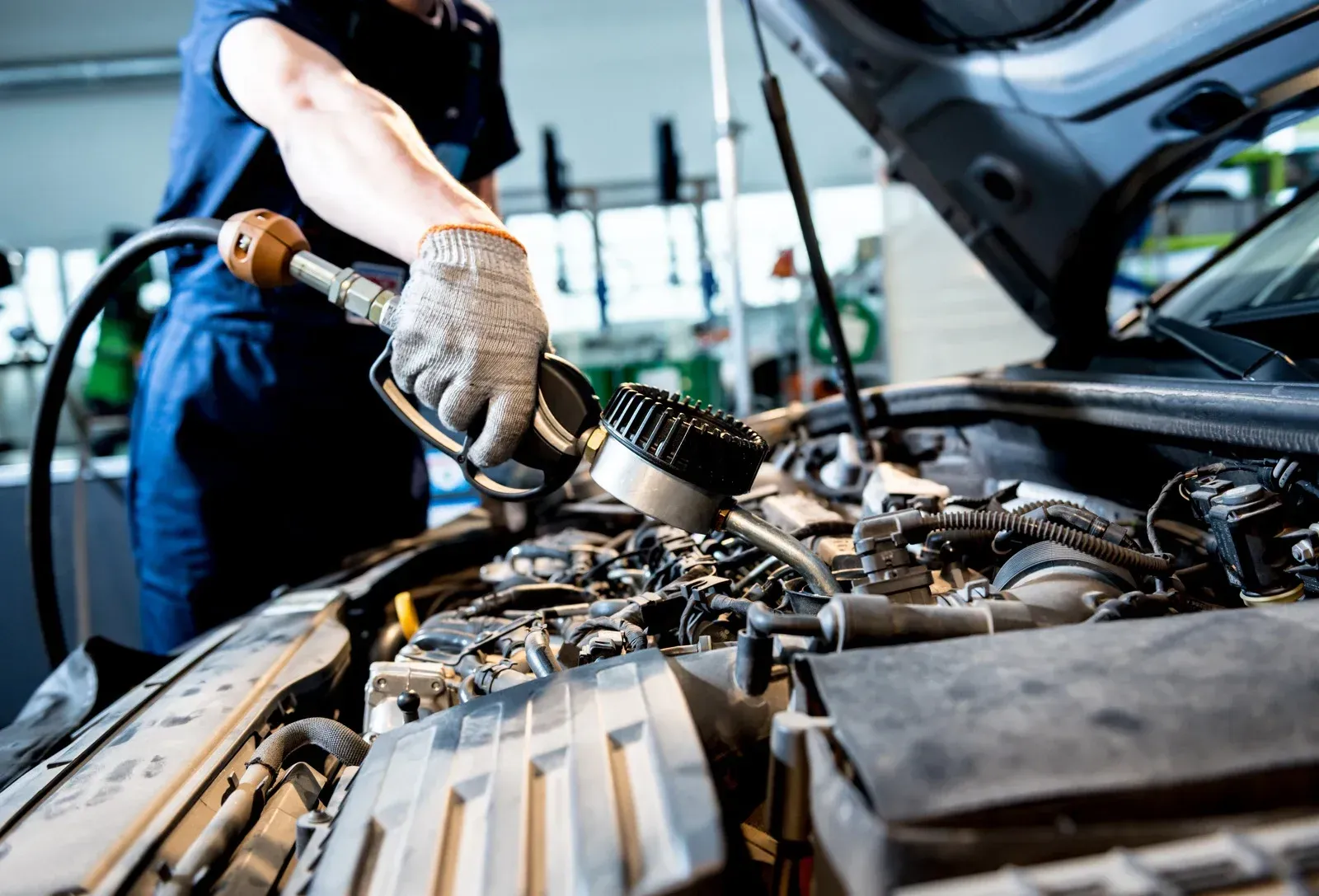 A man is working on the engine of a car in a garage.