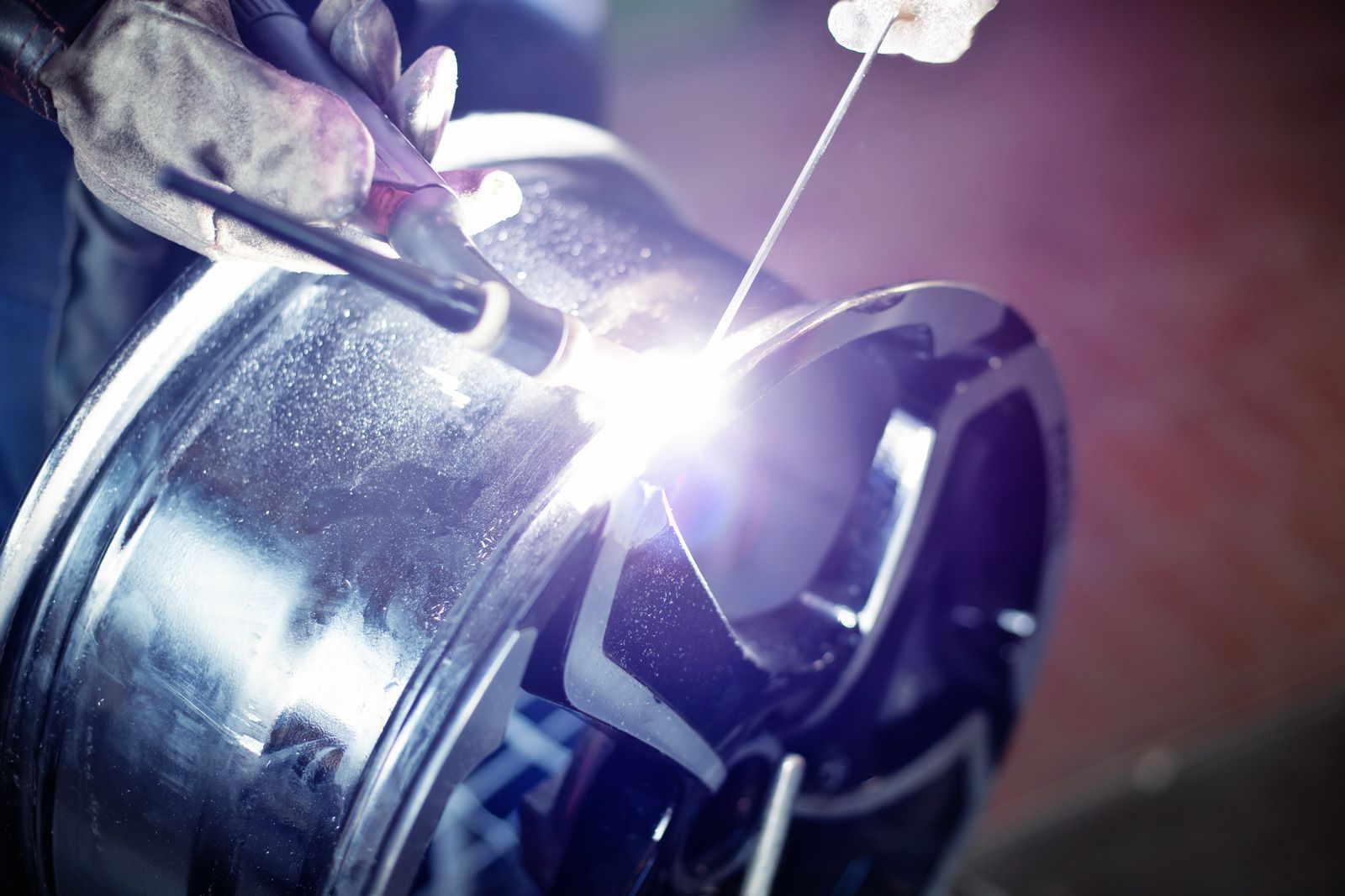 A person is welding a wheel with a welding machine.