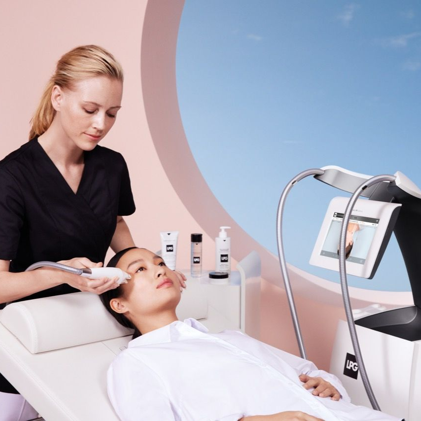 Femme recevant un soin du visage d'une technicienne, entourée de produits et d'un dispositif médical.