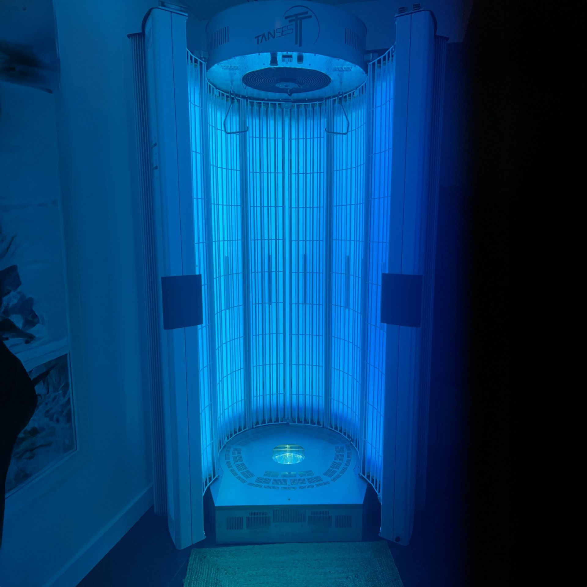 Un solarium avec des lumières bleues éclatantes. Dans une pièce aux rideaux blancs.