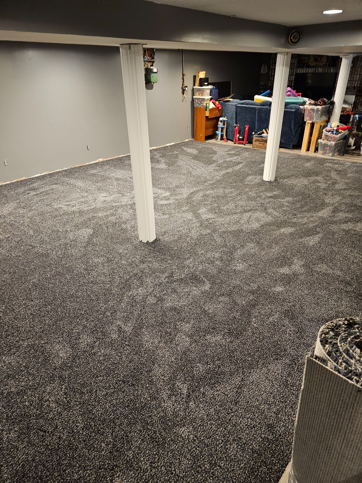 A basement with a carpeted floor and a living room.