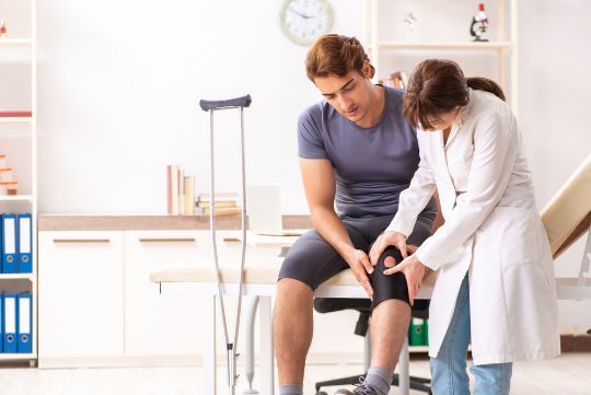 A Doctor Is Examining A Patient 's Knee In A Hospital — Physiocare In Maroochydore, QLD