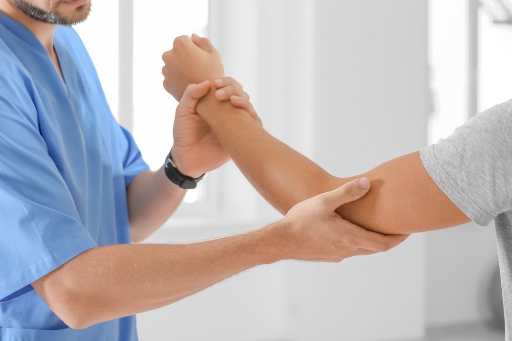 A Doctor Is Examining A Patient 's Elbow In A Hospital — Physiocare In Maroochydore, QLD