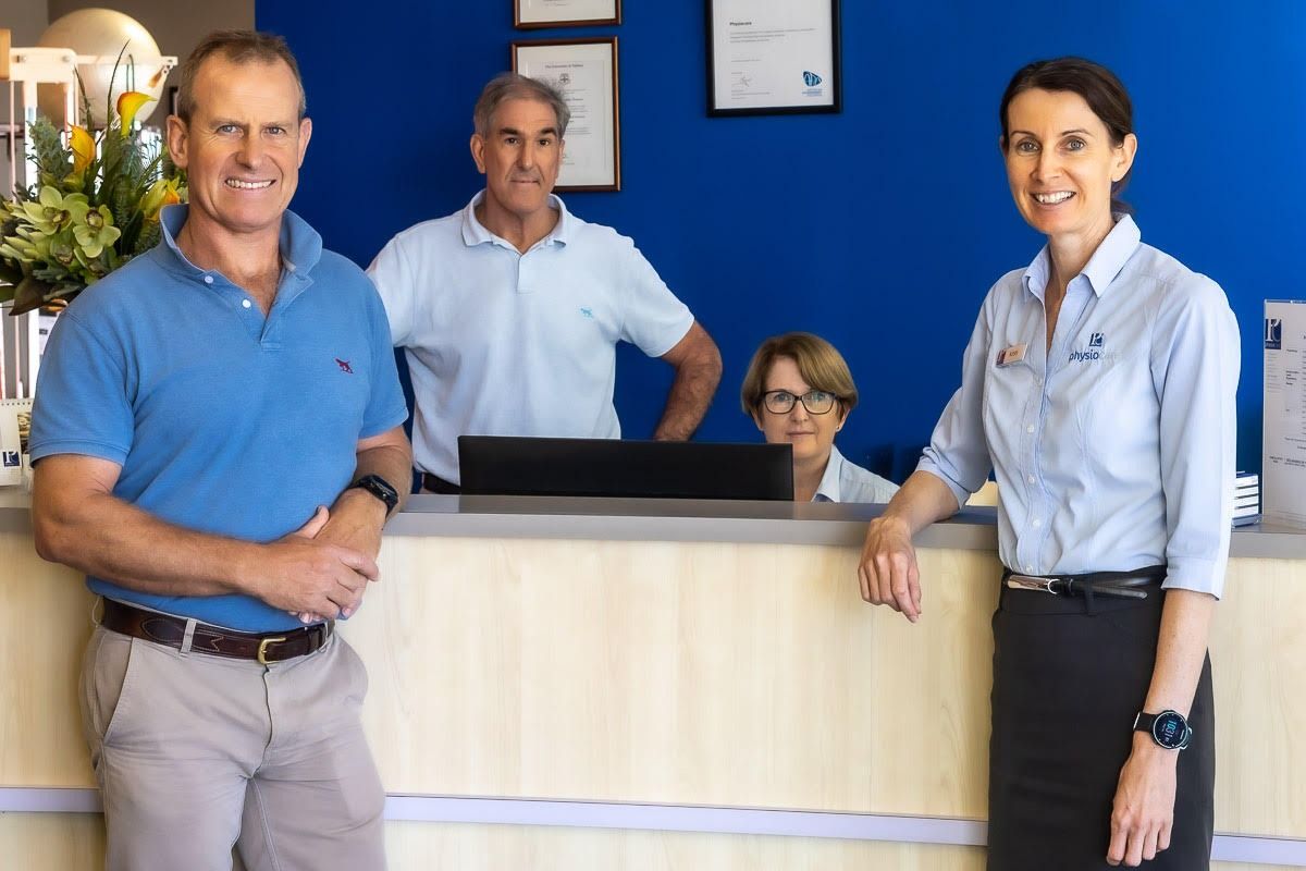 A Man And A Woman Are Standing In Front Of A Reception Desk — Physiocare In Maroochydore, QLD