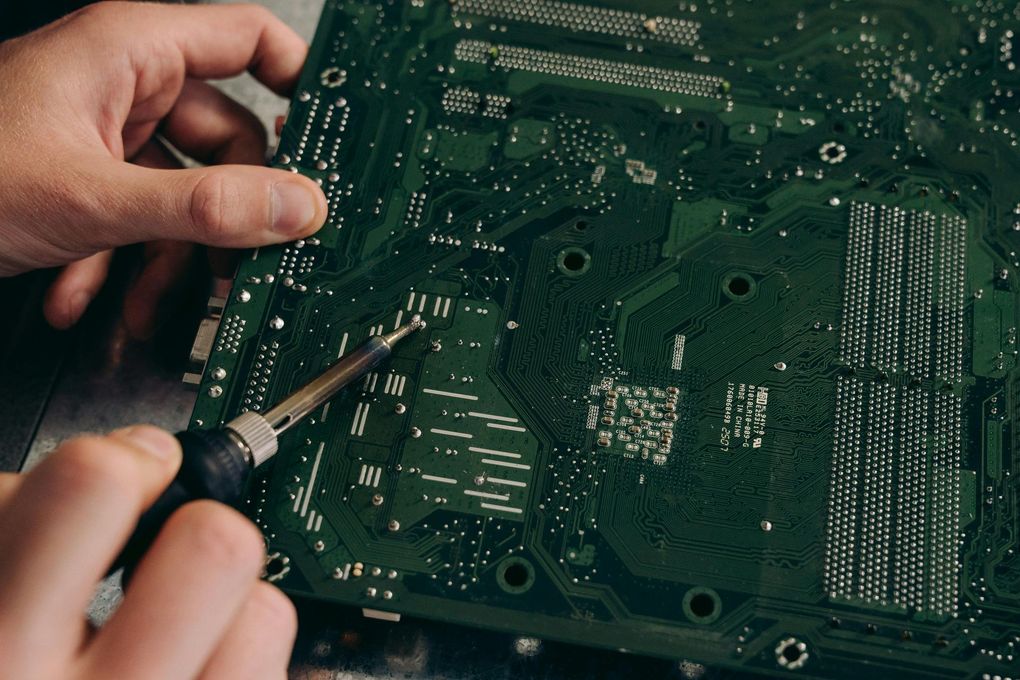 A person is working on a motherboard with a soldering iron.