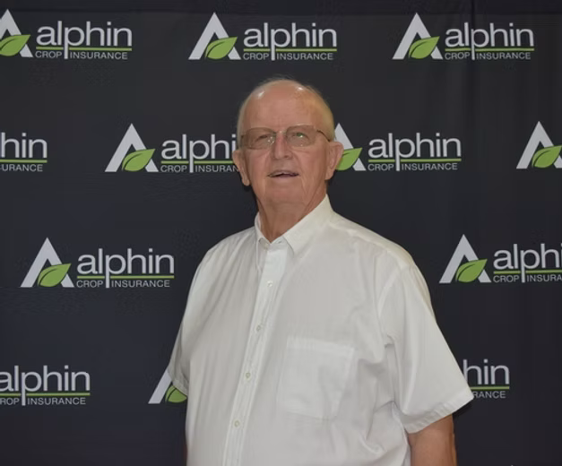 Man in a white shirt and glasses standing in front of a backdrop with the 