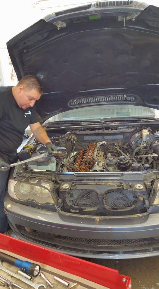 Technician Inspecting Engine Bay During Repair Service | New Dimensions Automotive
