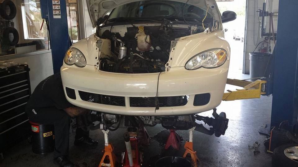 White Vehicle Raised For Front-End Repair Service | New Dimensions Automotive