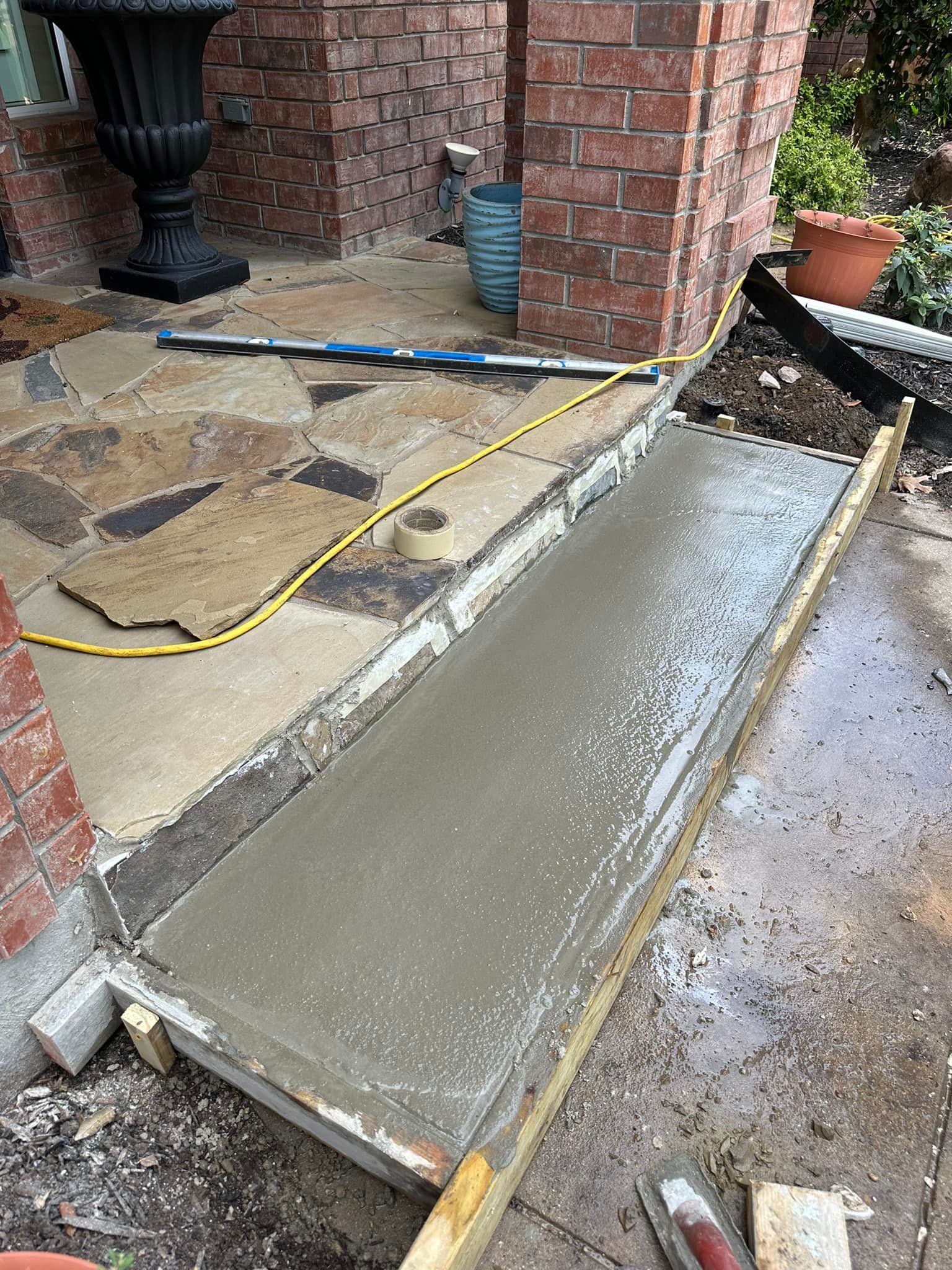 A concrete ramp is being built in front of a brick building.