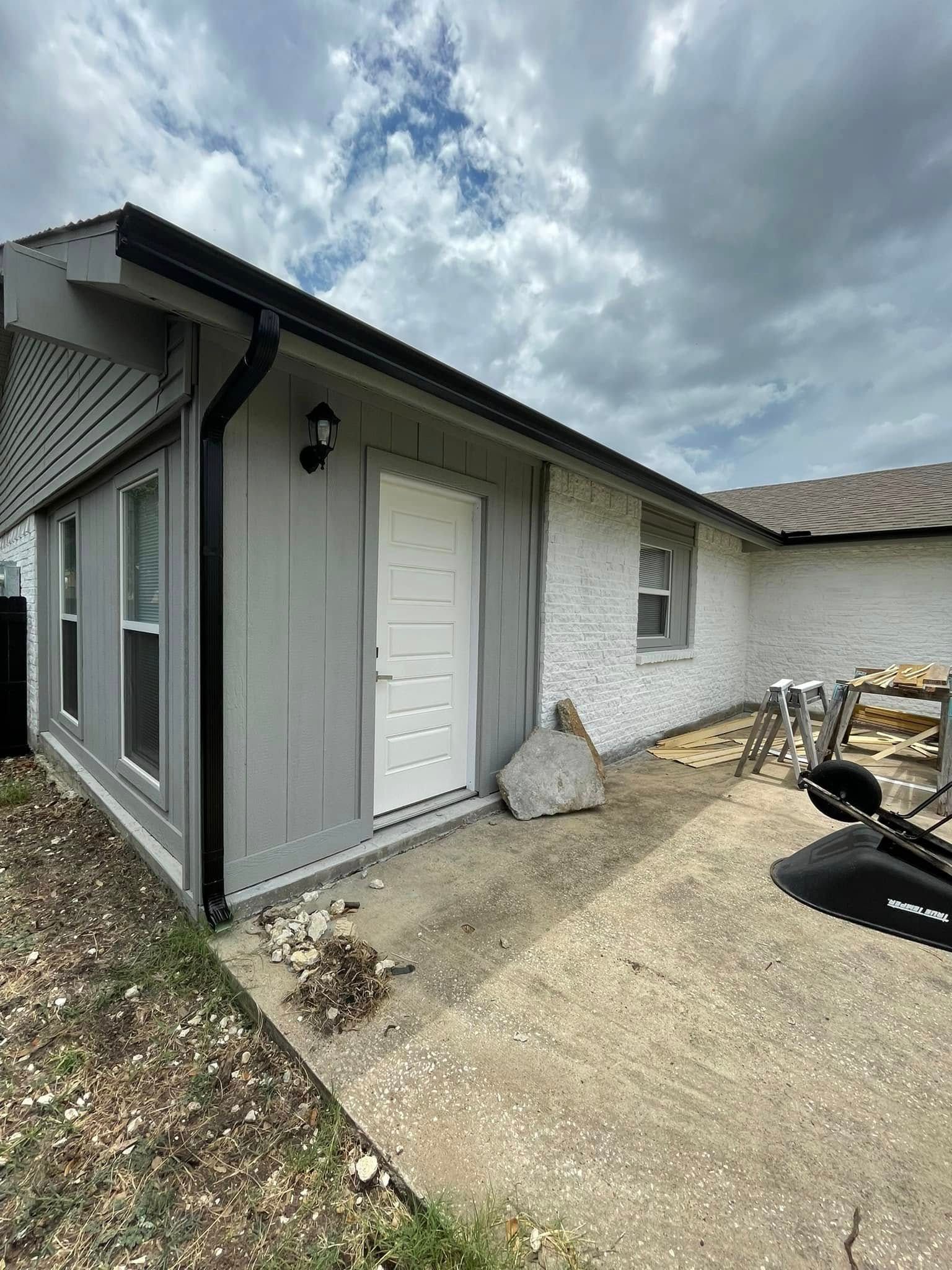 A large house with a garage and a driveway on a rainy day.