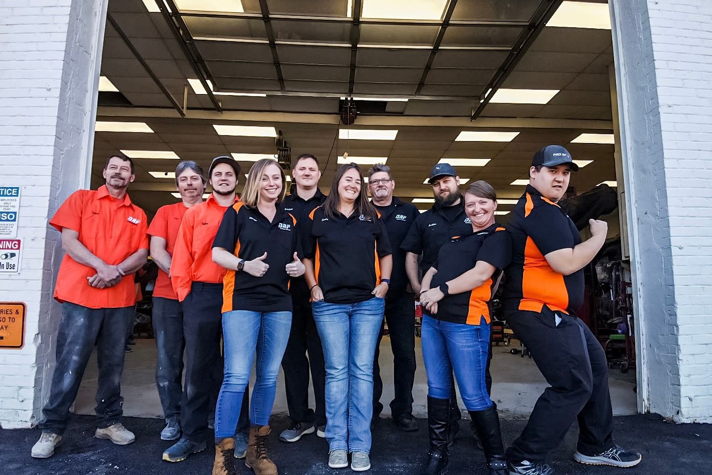 A group of people are posing for a picture in front of a garage door.