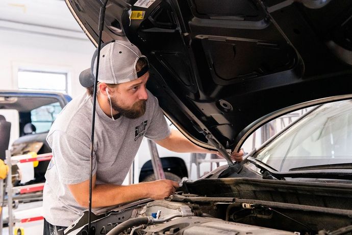 A man is working on a car with the hood open.