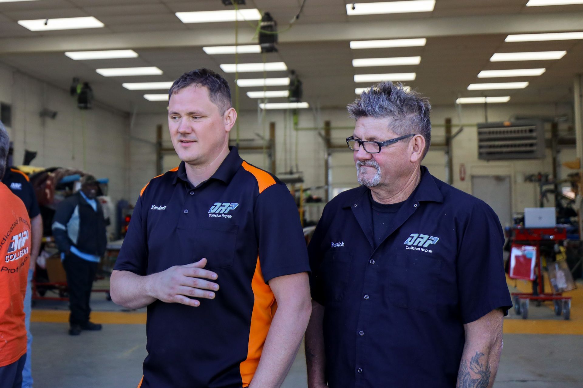 Two men are standing next to each other in a garage.