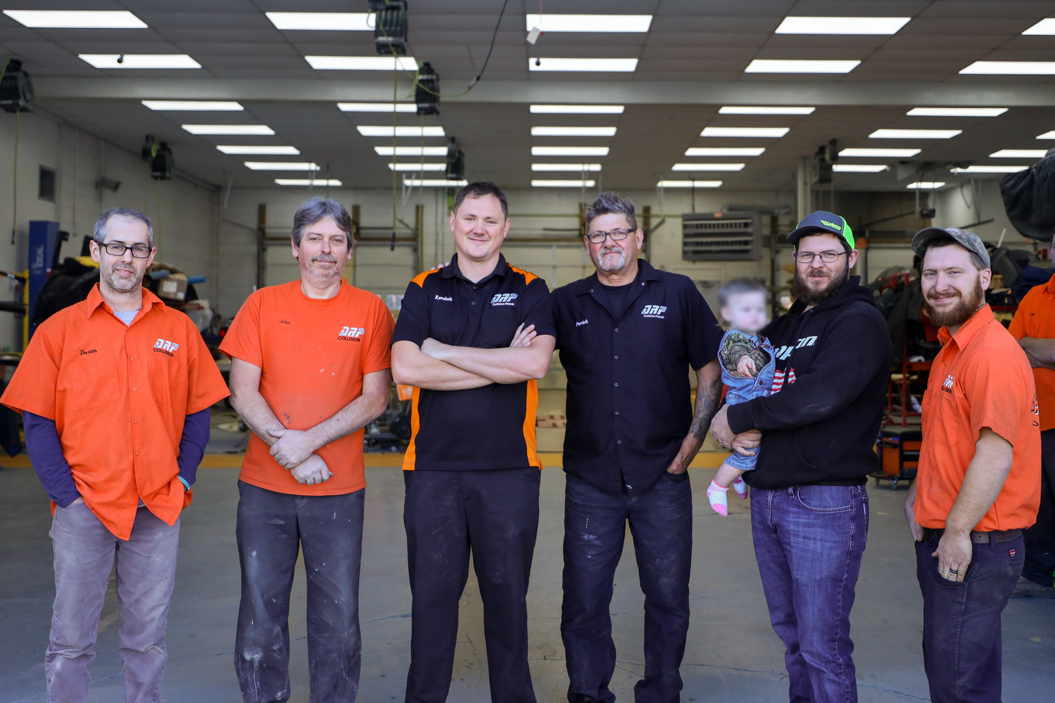 A group of men are posing for a picture in a garage.