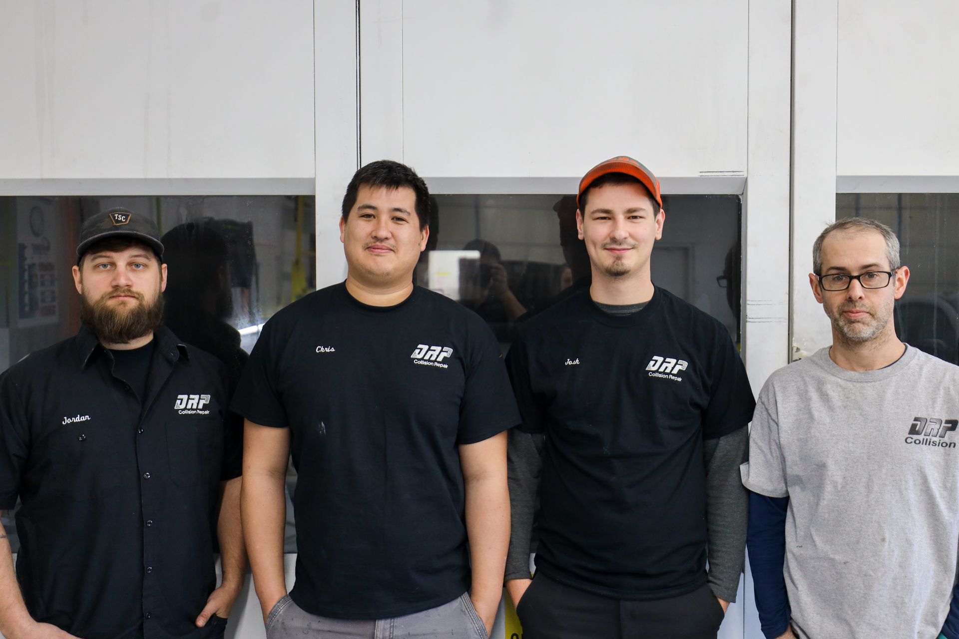 A group of men are standing next to each other in front of a window.