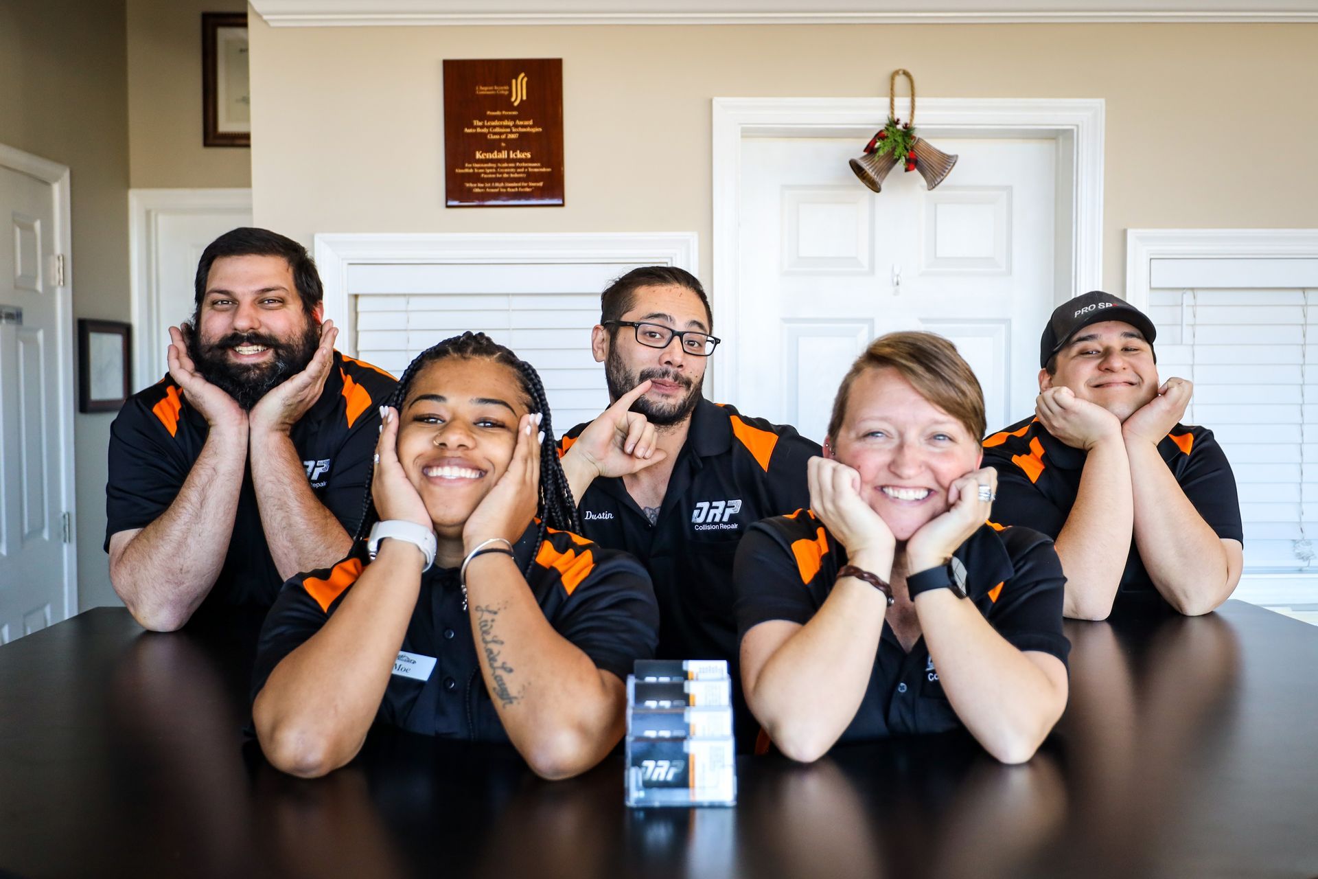 A group of people are sitting at a table with their hands on their faces.