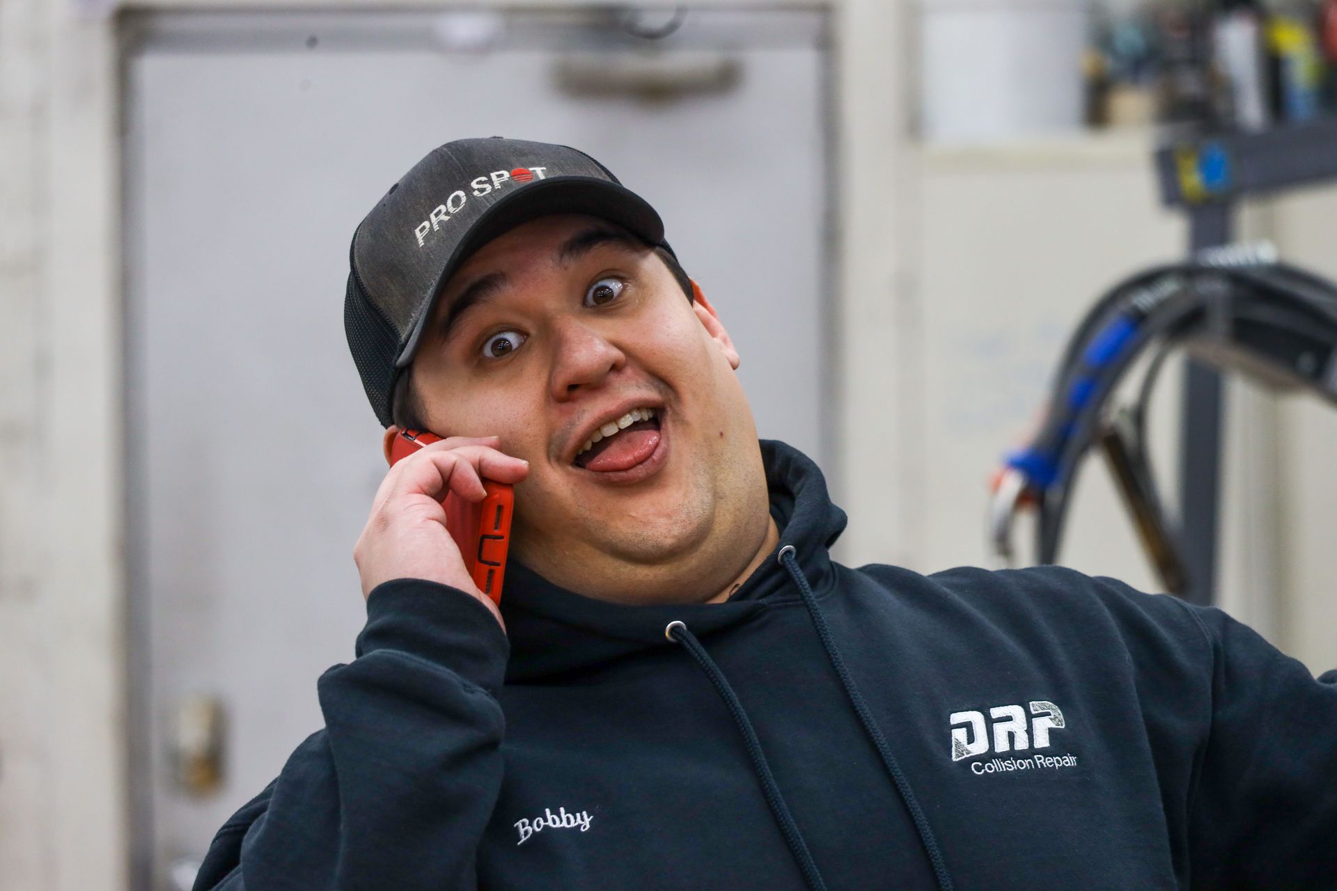 A man wearing a hat and a hoodie is talking on a cell phone.