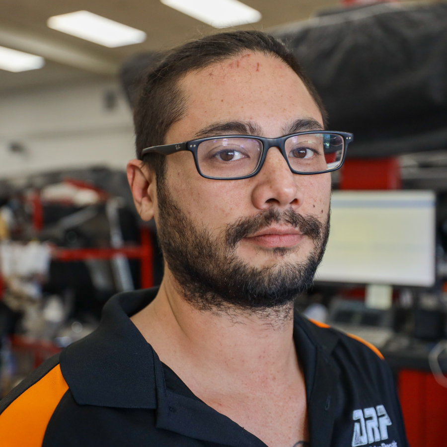 A man with glasses and a beard is wearing a black and orange shirt