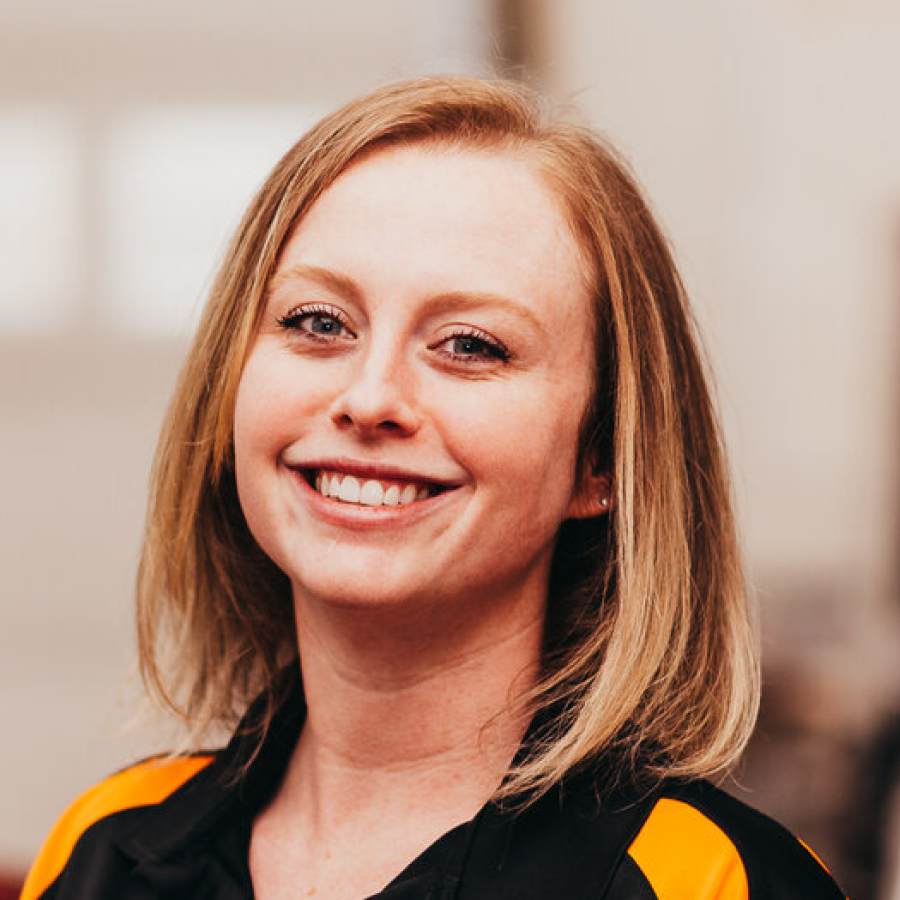 A woman wearing a black and yellow shirt is smiling for the camera.