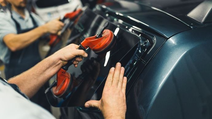 A man is installing a new windshield on a car.