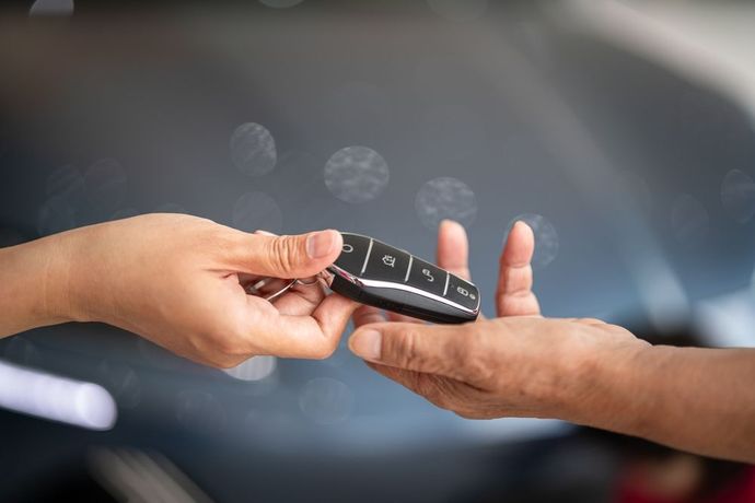 A person is handing a car key to another person.