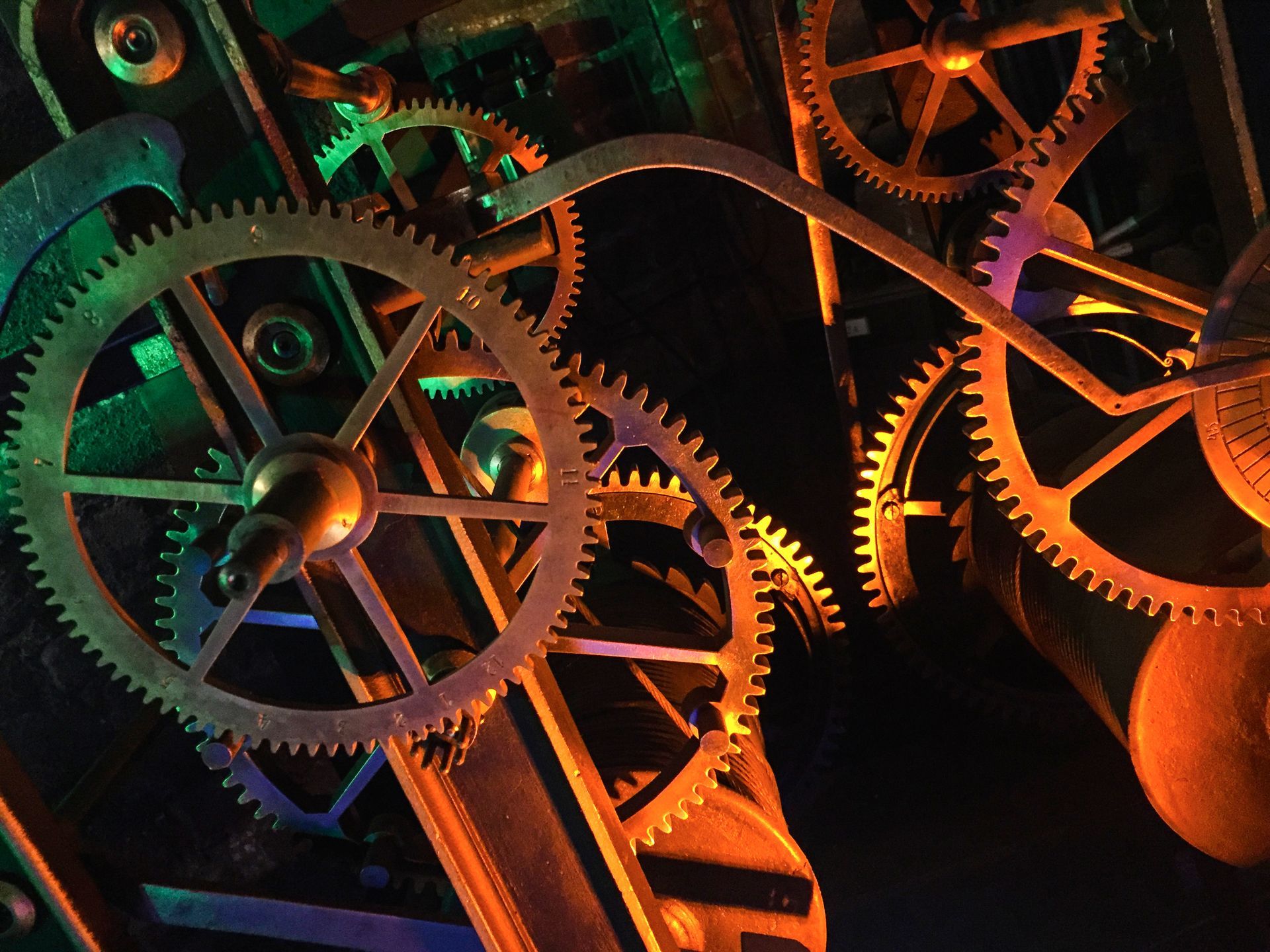 Close-up of gears, some illuminated with orange and green light, creating a mechanical, intricate design.