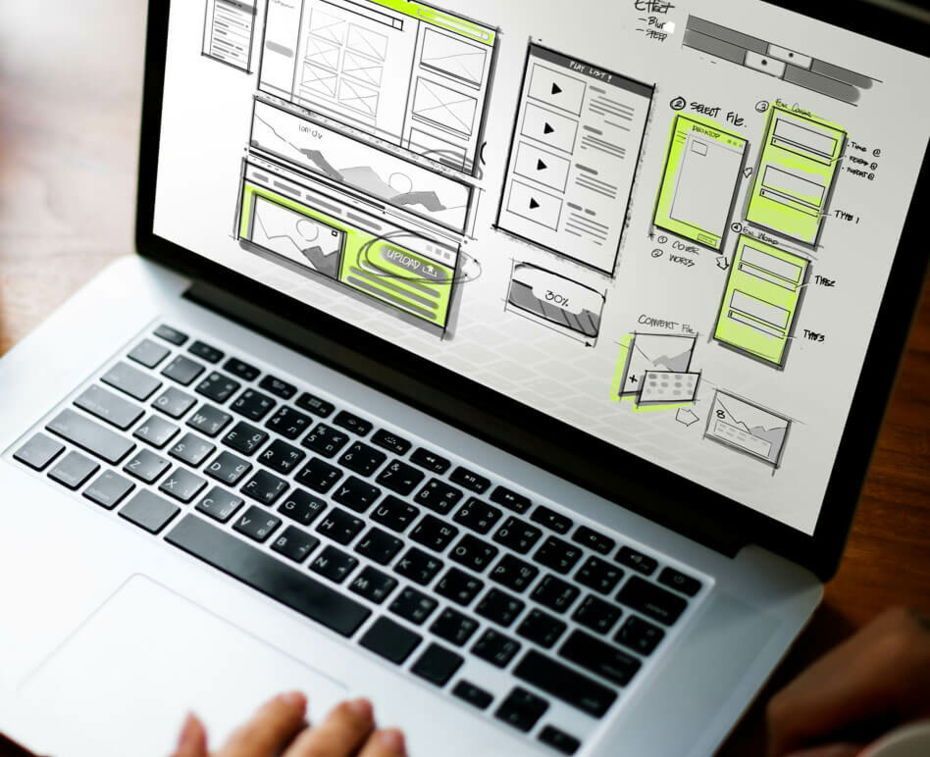 A person is using a laptop computer with a drawing on the screen to create innovative web design.