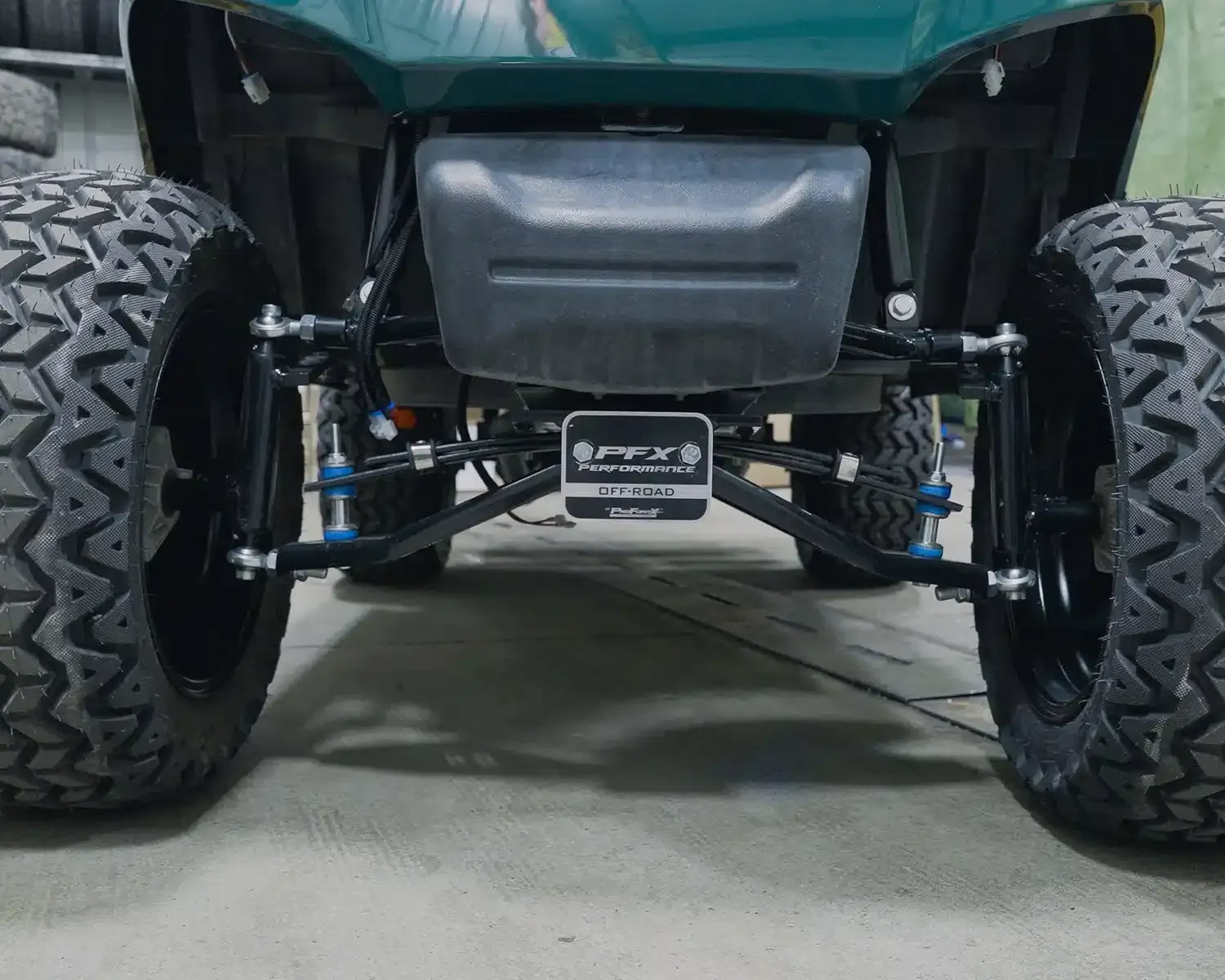 A green golf cart is parked in a garage | Midwest Truck and Tire