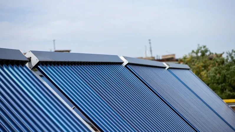 А solar water heating collectors, equipped with blue vacuum tubes, are installed on a rooftop to harness solar energy, converting it into heat for domestic heating and hot water systems