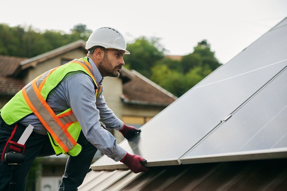 Male technician mounting solar panels on the roof of a house. Copy space.