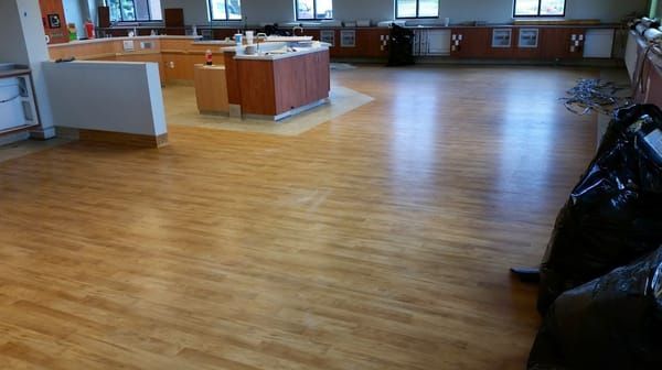 A large room with a wooden floor and a black bag on the floor.