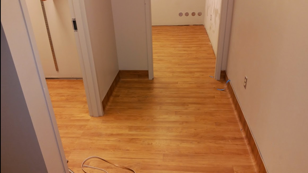 A hallway with a wooden floor and white walls.