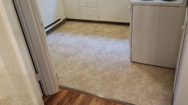 A kitchen with hardwood floors and a stove and refrigerator.