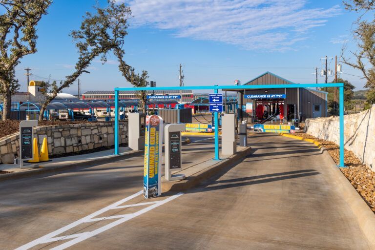 Car wash entrance with blue overhead structures and access gates.