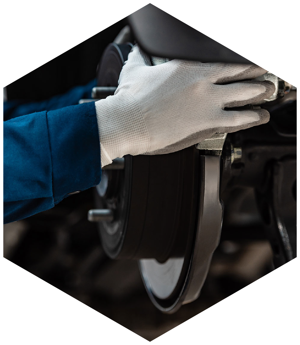 Mechanic wearing white gloves working on a car's brake system.