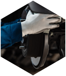 Mechanic wearing white gloves working on a car's brake system.