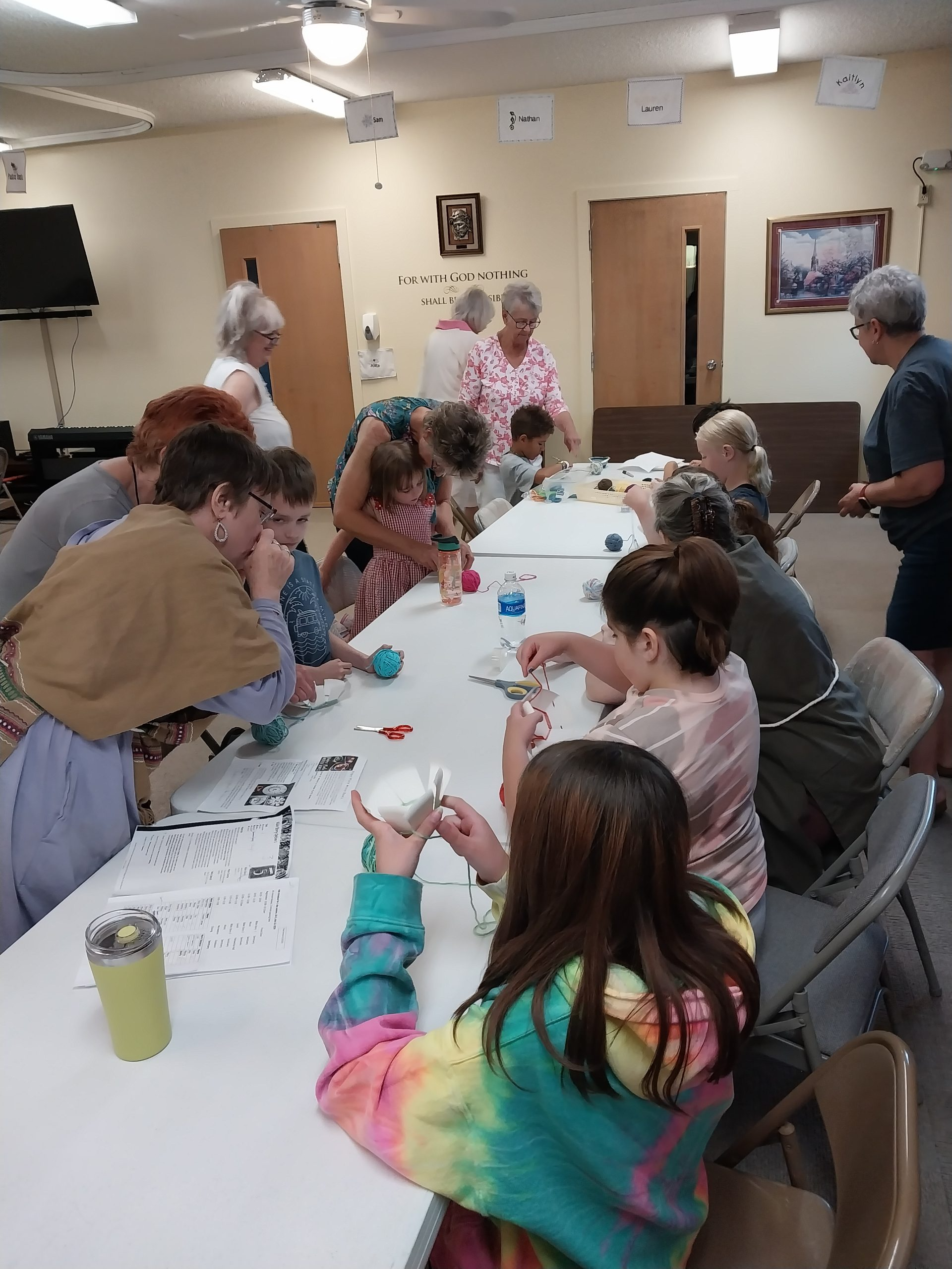 People gathered around a long table, crafting together in a brightly lit room.