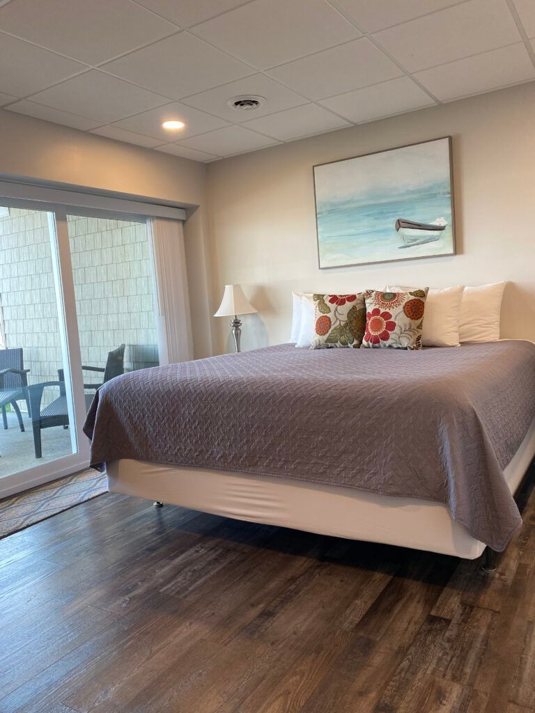 A bedroom with a king size bed and a sliding glass door leading to a balcony.