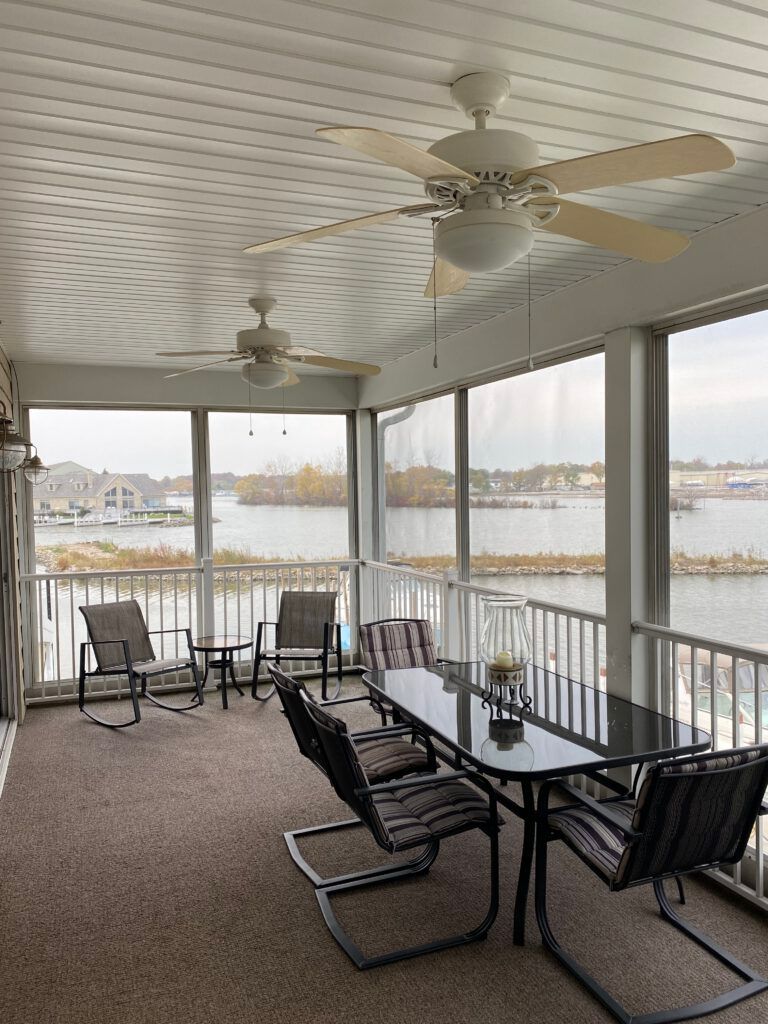 A screened in porch with a table and chairs and a view of the water.