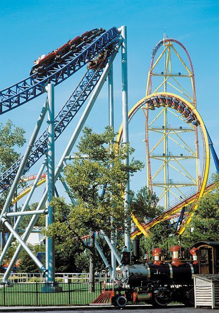 A roller coaster at an amusement park with a train in the foreground
