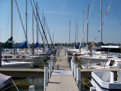 Many sailboats are docked at a marina on a sunny day