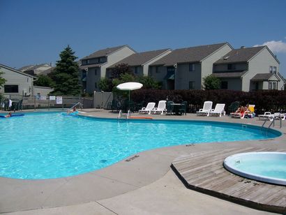 A large swimming pool surrounded by chairs and a fence with a view of the ocean