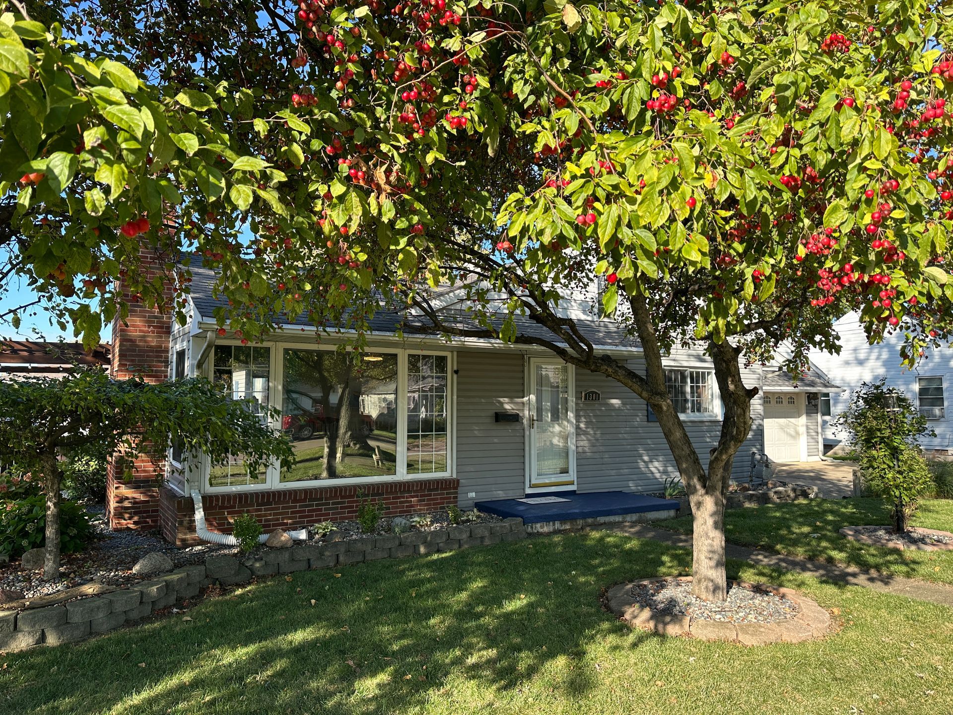 A large white house with black shutters and a blue sky in the background