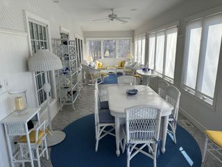A sun room with a table and chairs and a blue rug.