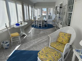 A living room with a wicker chair , ottoman , table and chairs.