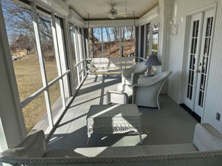 A screened in porch with wicker furniture and a ceiling fan.