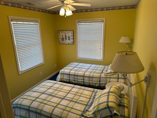 A bedroom with two beds , a lamp and a ceiling fan.