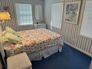A bedroom with a bed , dresser , mirror and striped walls.
