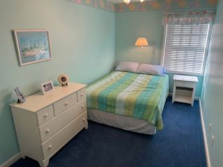 A bedroom with a bed , dresser , nightstand and window.
